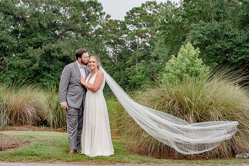 bride and groom with marsh in background, veil flowing