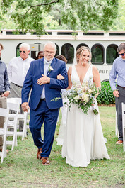 Bride walking down aisel with her father in a Savannah square with Old Savannah Trolley in background