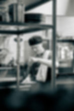 En svartvit bild på en kock som jobbar på restaurang.