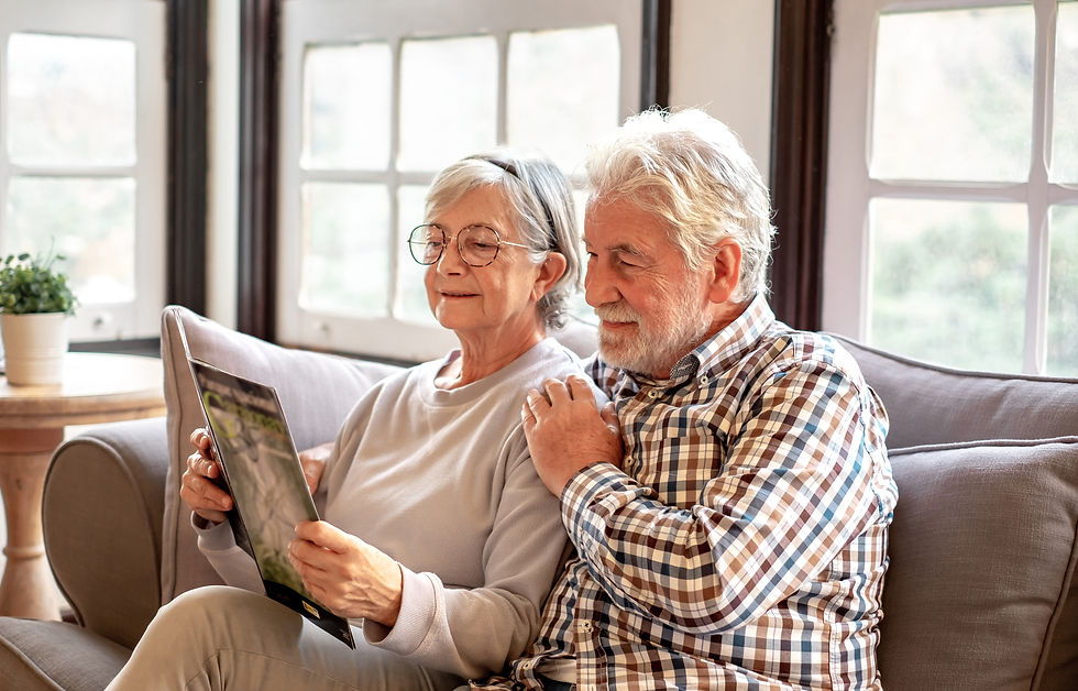 Smiling senior couple sitting together on the couch watching a brochure