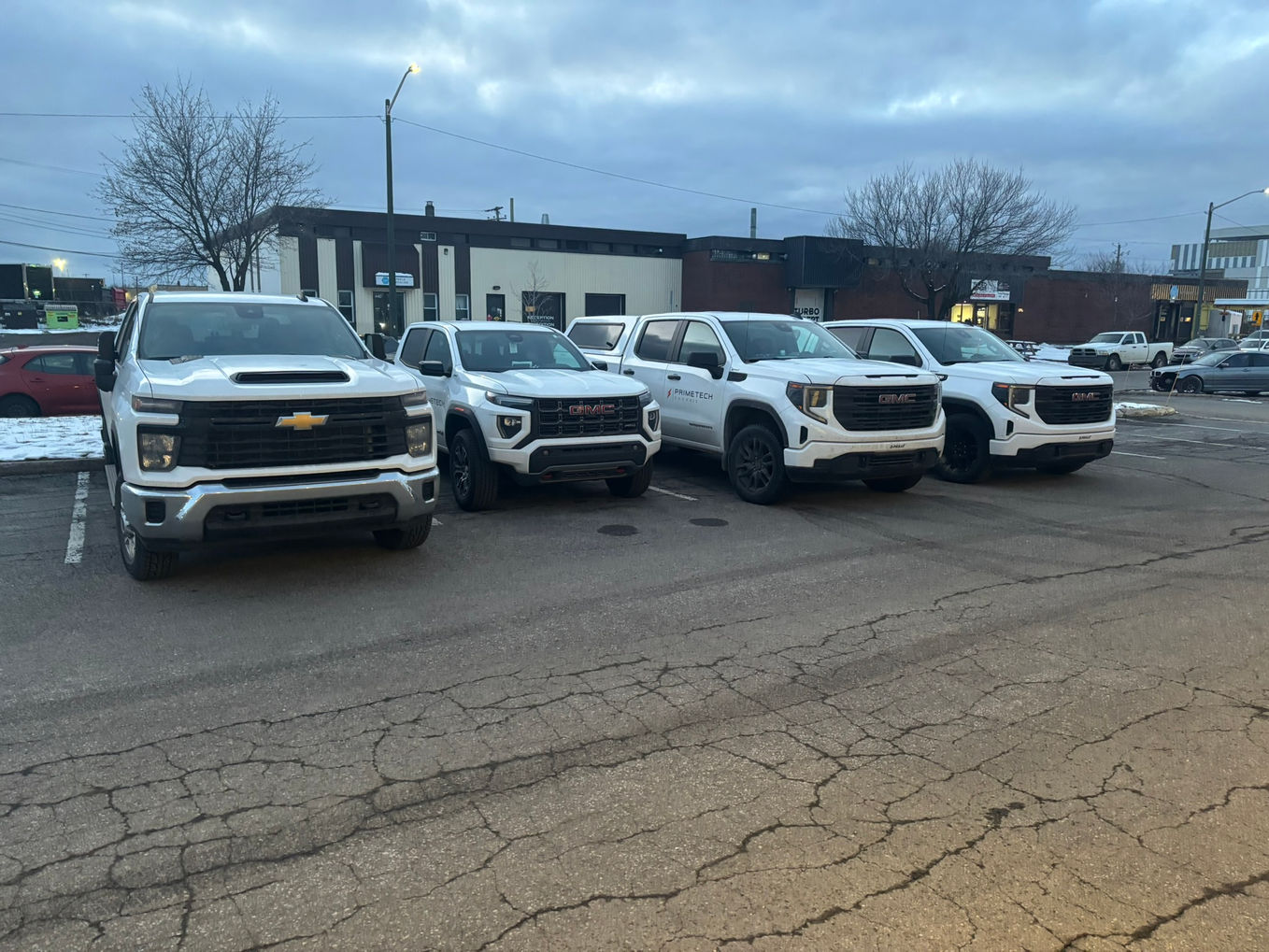 A row of white Chevrolet and GMC trucks in a parking lot.