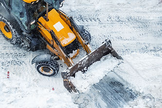 Chargeuse jaune effectuant le transport de neige.