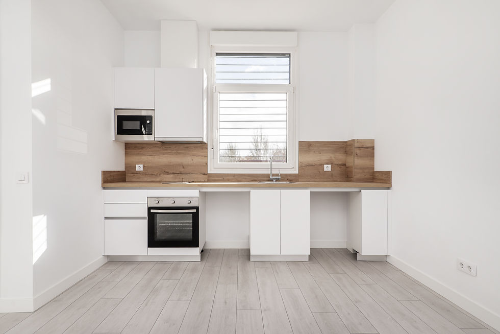 Front of a recently renovated kitchen with white wooden furniture, wooden countertop