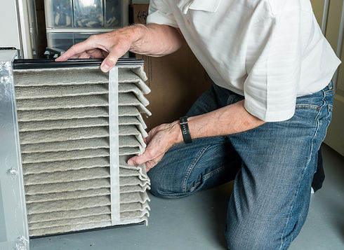 man changing a folded dirty air filter in the HVAC furnace system in basement of home