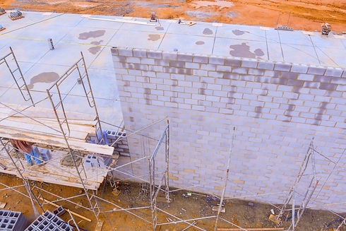 Bricklayers build concrete walls using concrete blocks while standing on scaffolds