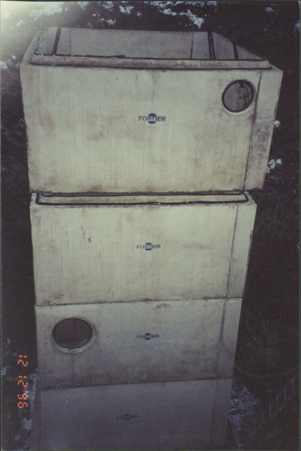 Deux sections de regard en béton empilées avec ouvertures circulaires.