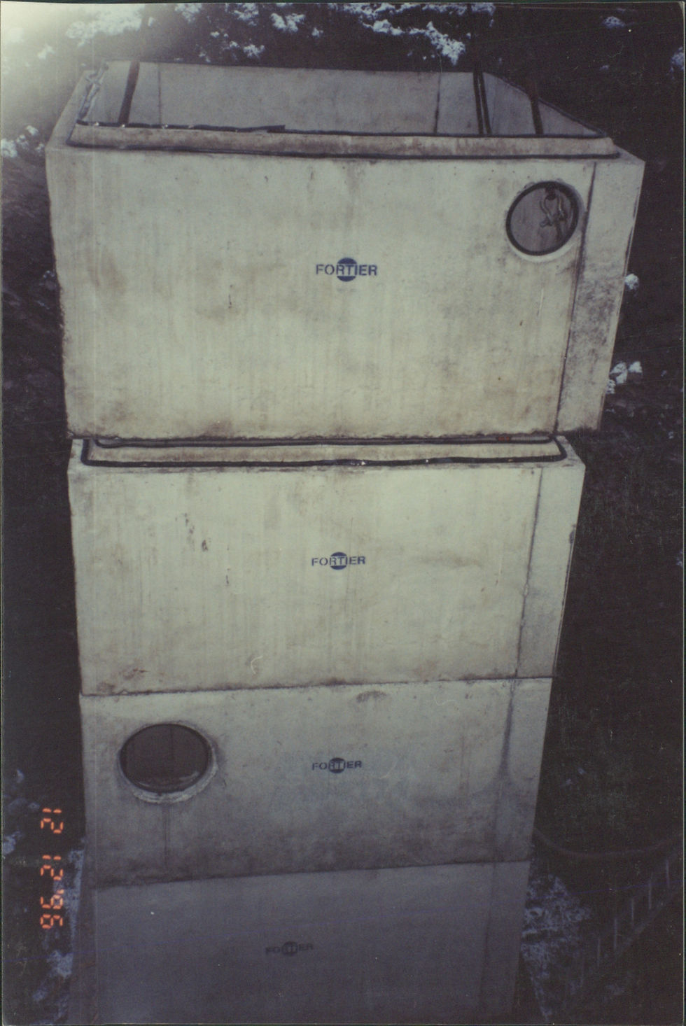 Deux sections de regard en béton empilées avec ouvertures circulaires.