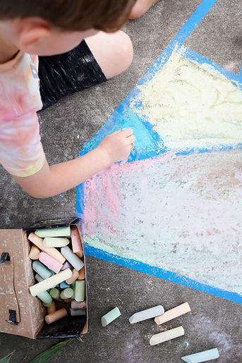 Kid painting concrete ground with a chalk
