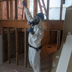 Worker in protective suit removing ceiling during renovation