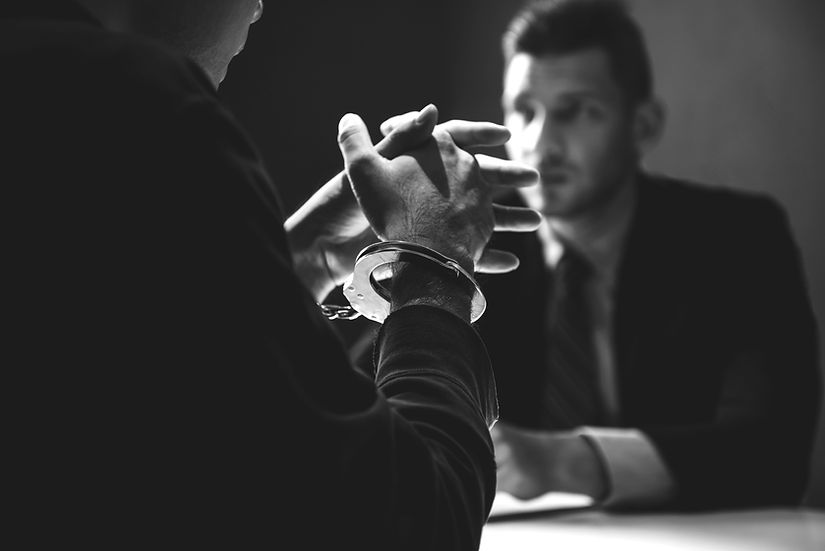 Criminal man with handcuffs being interviewed