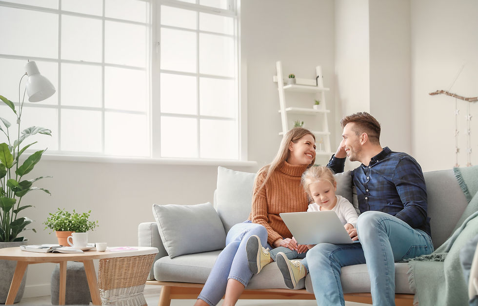 Happy young family with laptop sitting on sofa at home