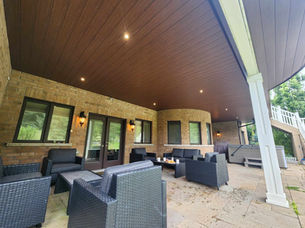 Outdoor patio with dark wicker furniture and wood ceiling