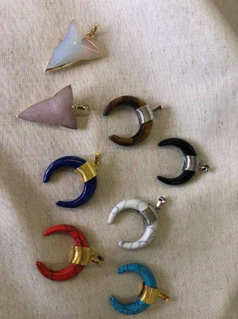 Colorful crescent moon and arrow-shaped stone charms on textile background.