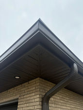 Dark brown soffit and gutter on a brick building corner