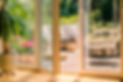 hanging armchair and a rattan sofa with cushions on a wooden patio behind the door