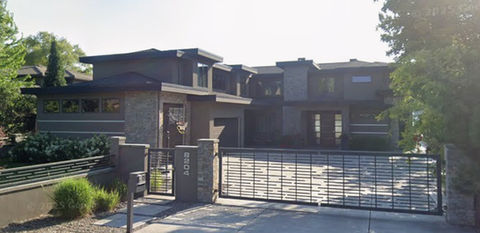 Large modern house with dark exterior and a metal gate.