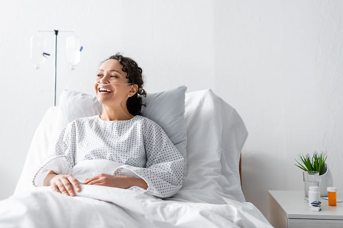 happy african american woman laughing while sitting in hospital bed