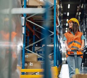 Female warehouse worker pulling pallet jack through a distribution center