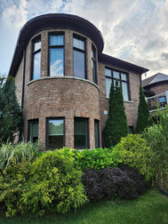 Modern brick house with a rounded bay window and lush garden