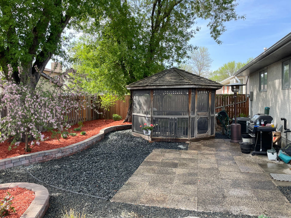 Wooden gazebo in a backyard setting; patios and sidewalks visible.