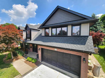 Modern two-story house with dark shingles and garage.