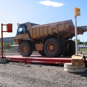 Large yellow dump truck on a scale in a construction area