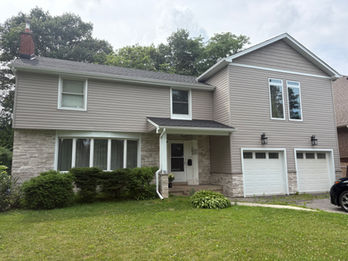 Two-story house with beige siding and white garage door.