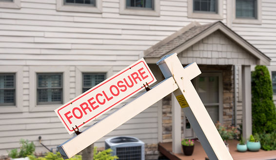 Mockup of a foreclosure sign in front of a modern townhome
