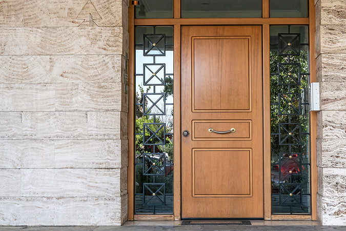 A classic design house entrance with a wooden door between glass openings.