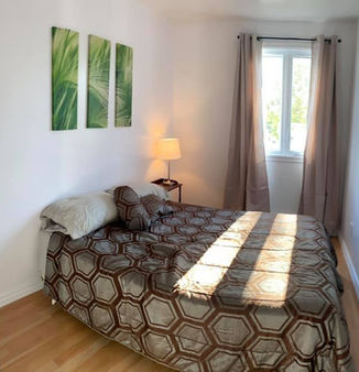 Chambre d'un appartement meublé avec lit double et tableaux.