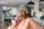 senior woman touching face, standing standing in kitchen