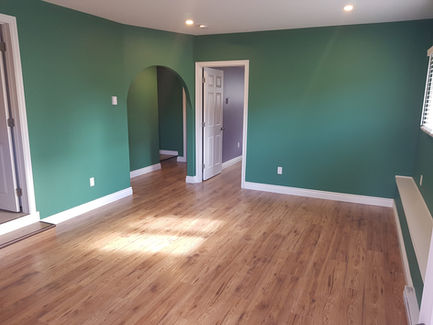 Empty room with green walls, wood floor, and doorways