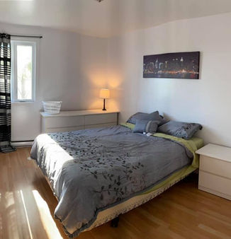 Chambre d'un appartement meublé avec lit double et lampe.