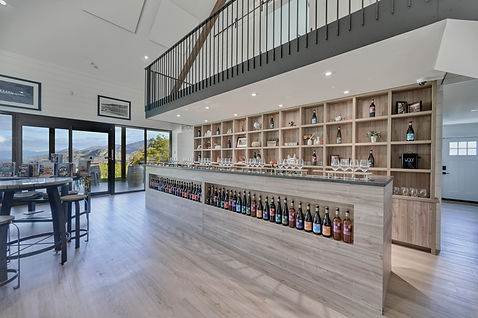 Modern wine bar with oak shelving and glass doors.