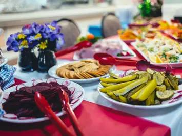 Buffet table with sliced beets, pickles, crackers, and flowers