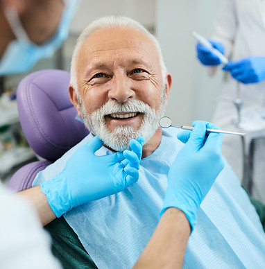 Happy senior man having dental treatment at dentist's office.