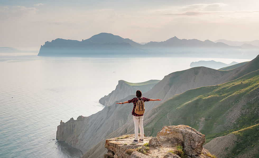 happy woman with a backpack standing on a rock