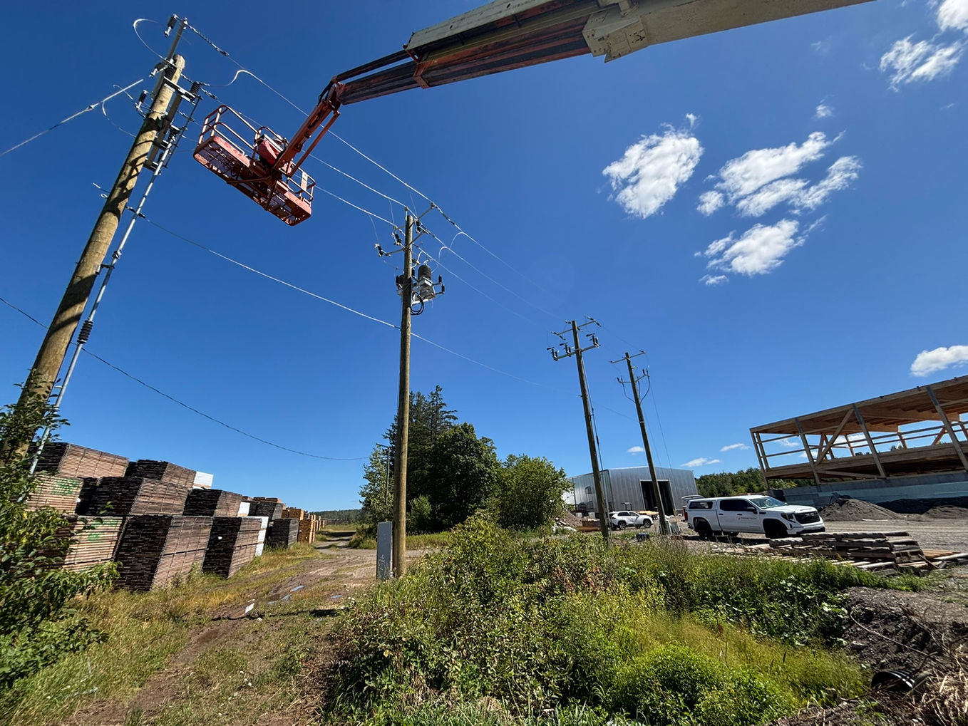 Technician on an aerial platform working on electricity poles in clear weather.