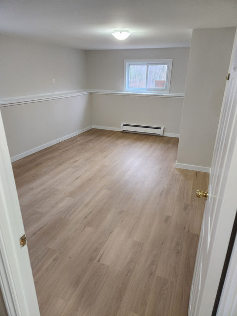 Empty finished basement room with wood floors