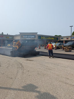 Paving the parking lot, workers pave surface with machinery in progress. Tri City Paving Inc