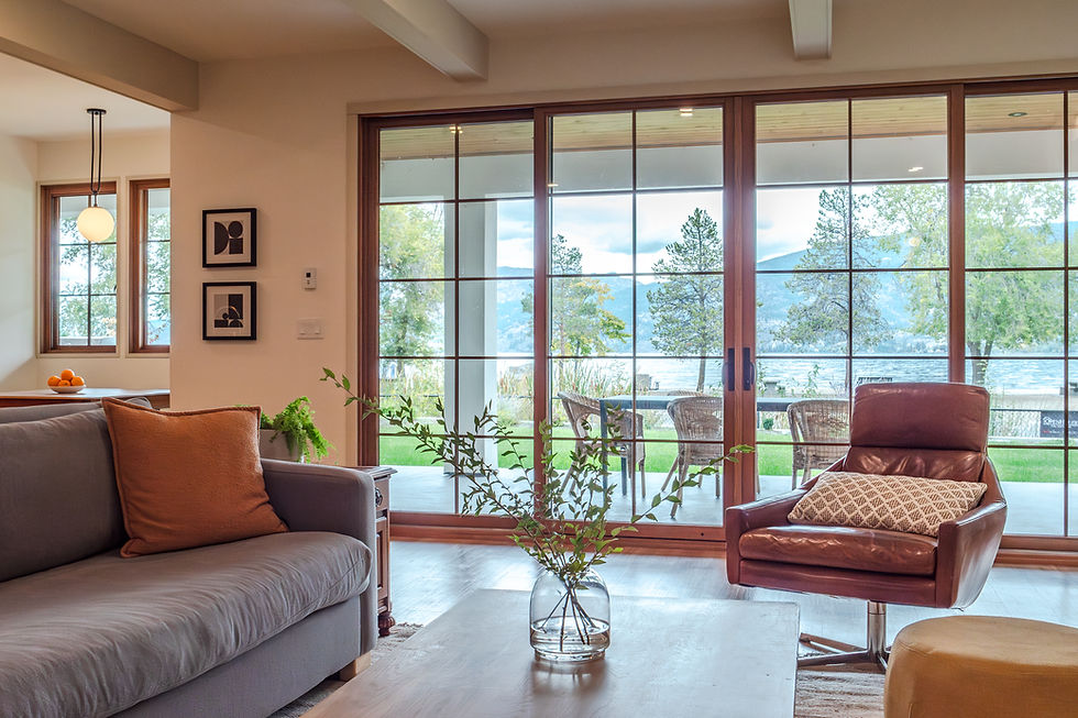 Modern living room with grey sofa, lake view, and glass doors.