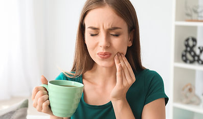 Young woman with sensitive teeth and cup of hot coffee at home