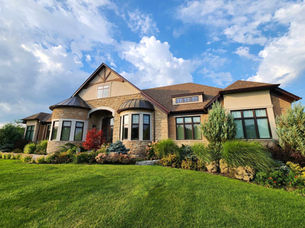 Large luxury home with stone facade and landscaped lawn.