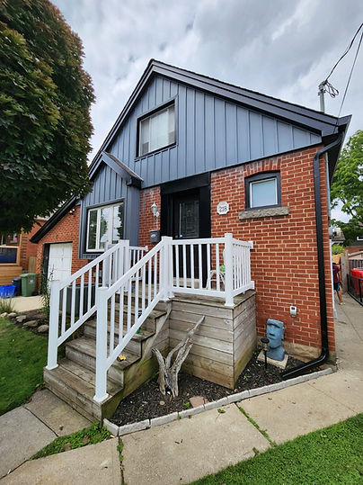 Red brick house with blue vertical siding and white porch railings