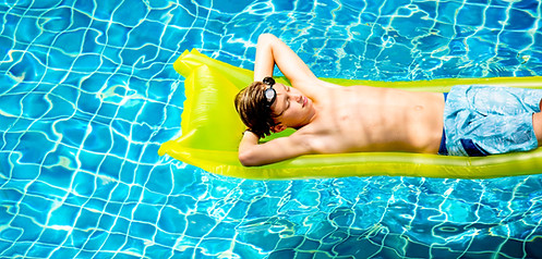 Young caucasian boy enjoying floating in the pool with tube