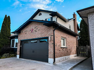 Two-story brick house with a black garage door.