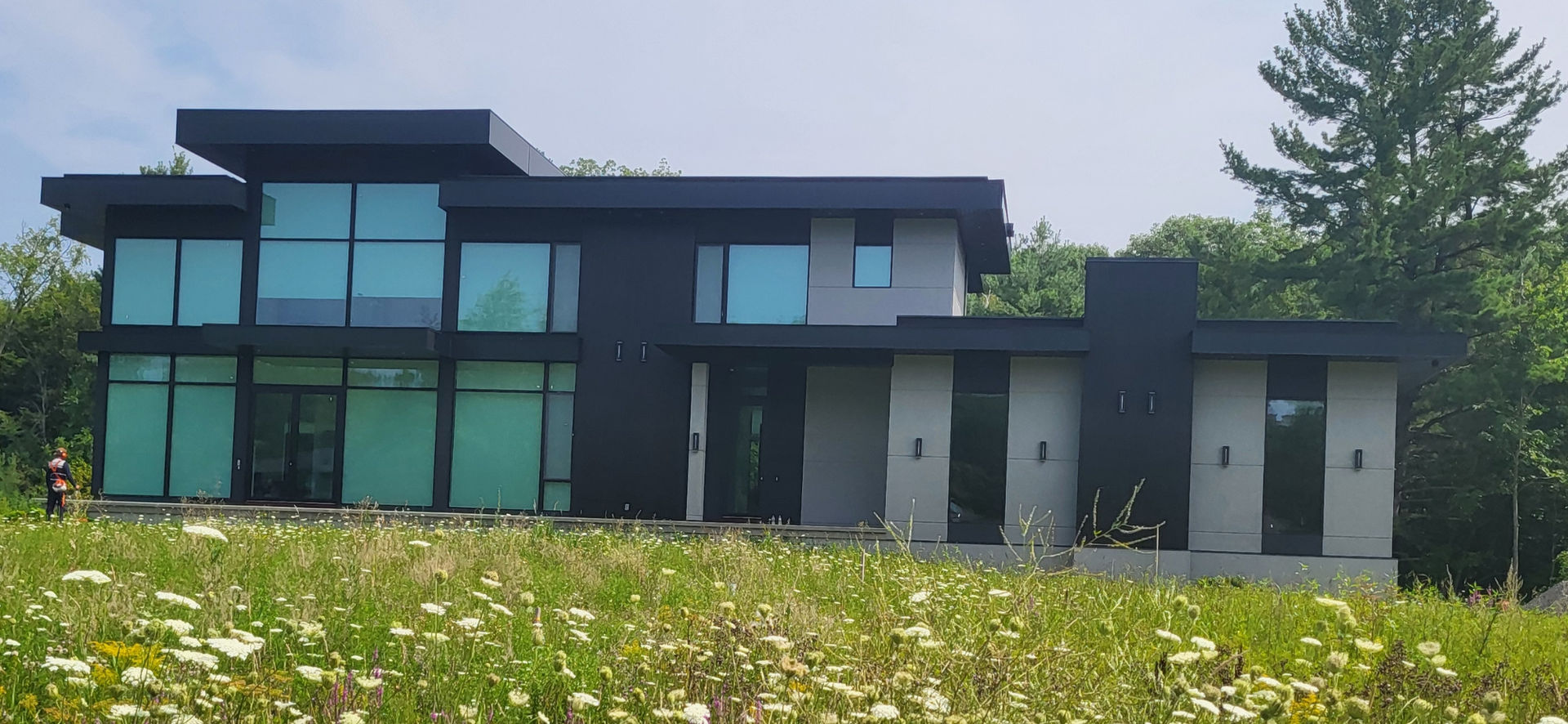 Modern two-story house with large windows and a grassy lawn.