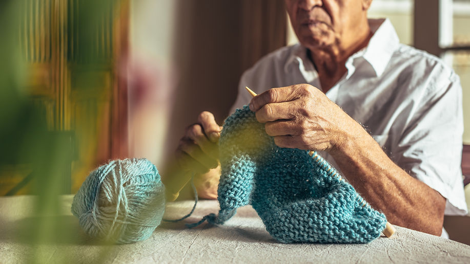 Retired man knitting at home 