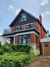 Red brick house with dark trim and a second-floor balcony