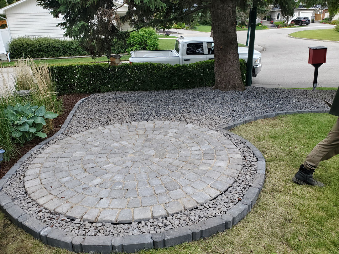 Circular stone paver patio surrounded by grey gravel.